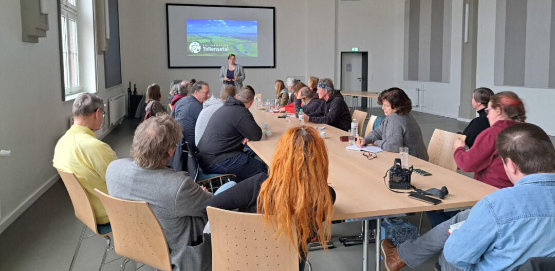 Foto des Tischs mit den Akteuren während Anna Goedicke den Kulturgut Freiland e.V. vorstellt.