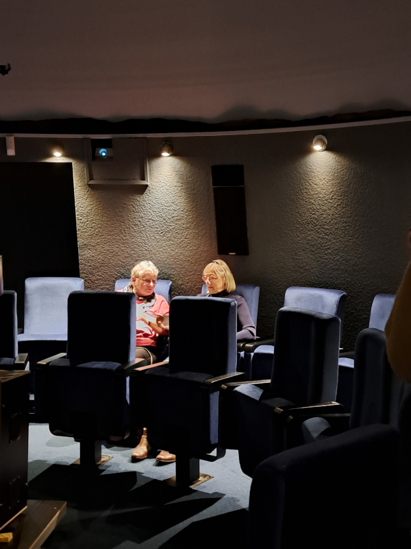 Foto der benannten Personen in den Sitzreihen des Planetarium